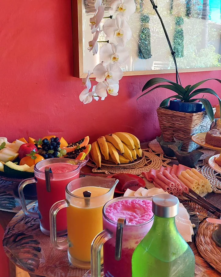 Mesa do café com sucos coloridos, frutas e orquídea