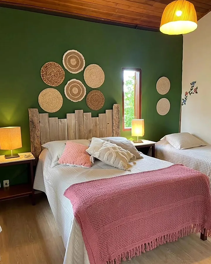 Suíte com cama de casal, colcha vermelha e luminária de palha
