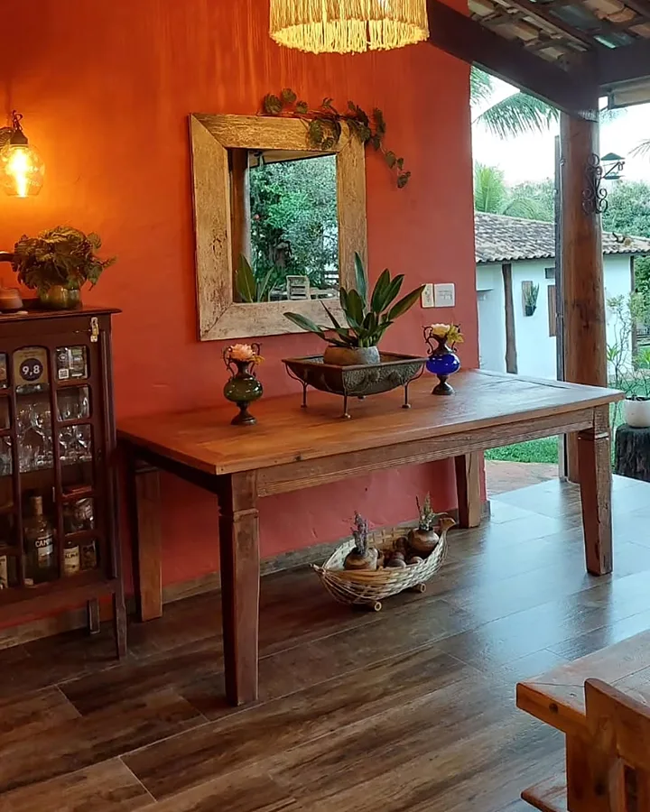 Sala de convivência com mesa de madeira e luminária de macramê